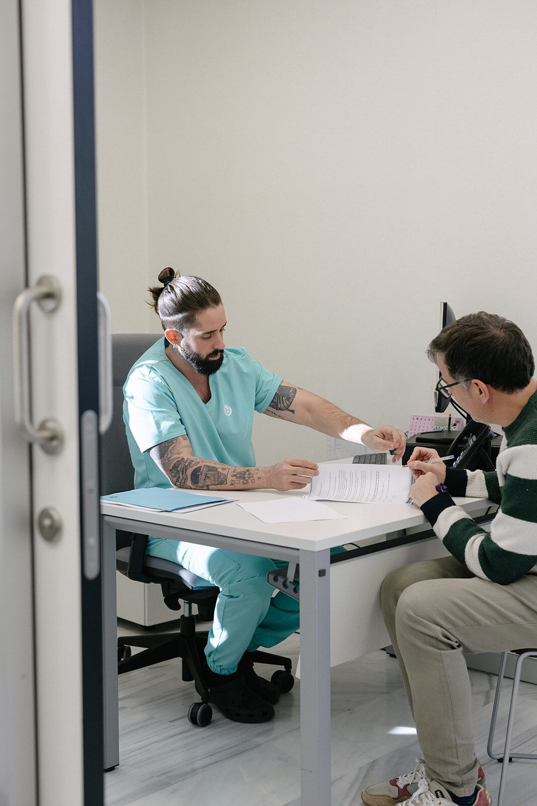 Dr. Jofré revisando documentación clínica con un paciente en consulta