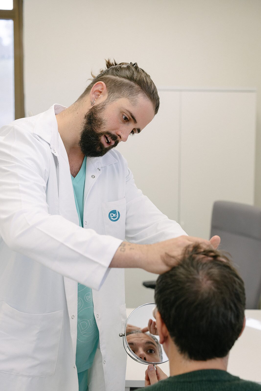 Dr. Jofré realizando exploración tricológica con espejo en consulta